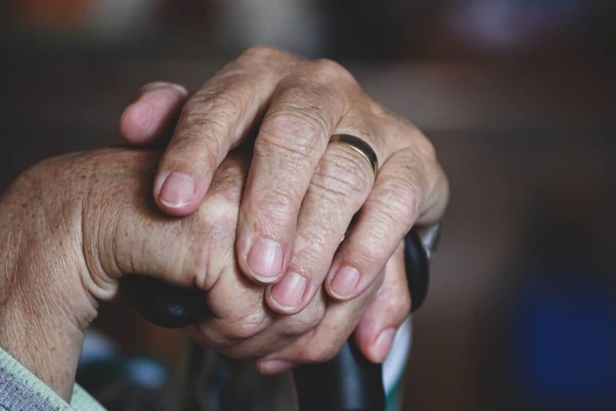 Mains d'une personne agée sur une canne