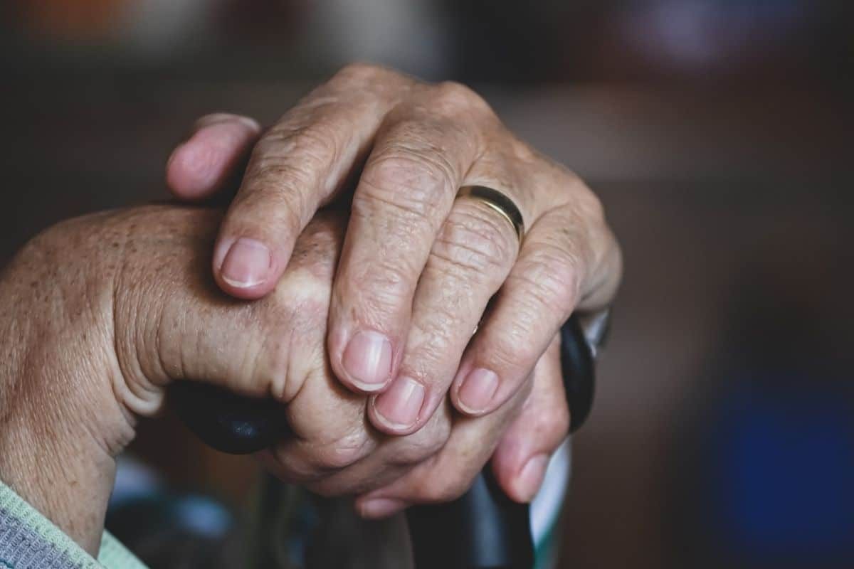 Mains d'une personne agée sur une canne